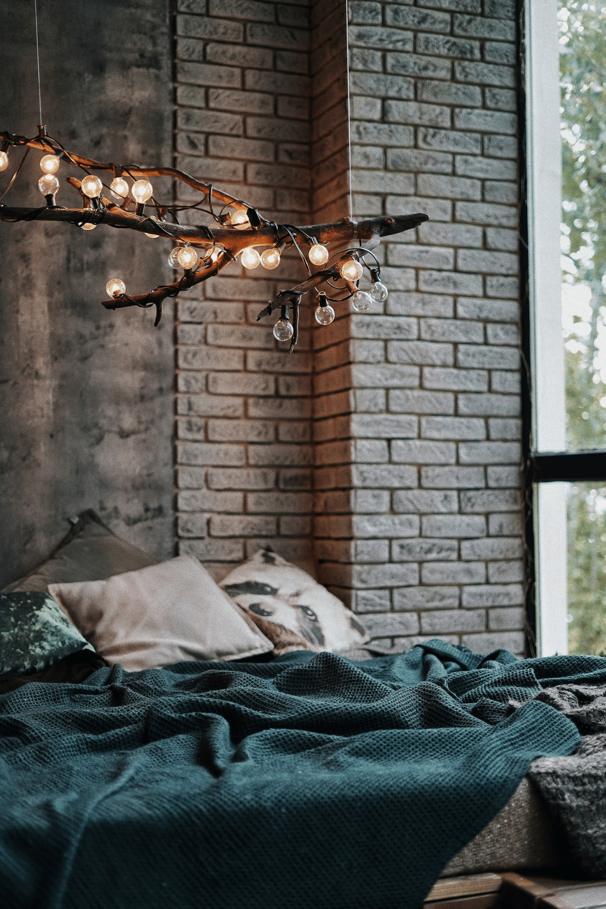 bedroom with stone brick detailing and a tree branch adorned with light bulbs as a hanging light feature