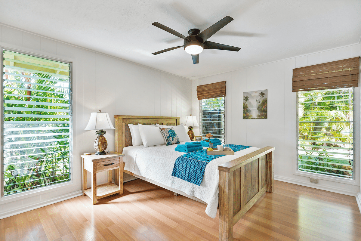 a bedroom with a neatly made bed and a ceiling fan light