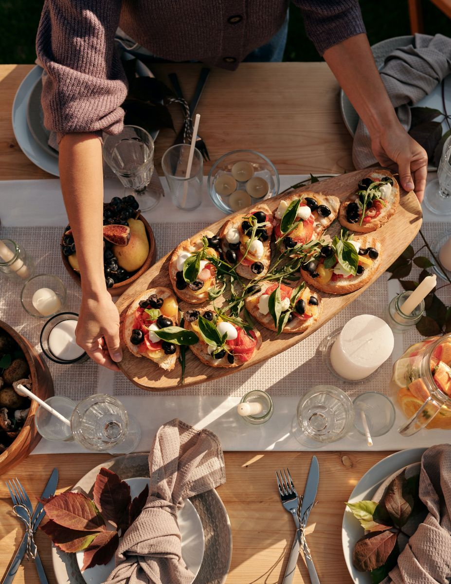 Cropped hands serving bruschetta on brown wooden board for Mother’s Day lunch celebration