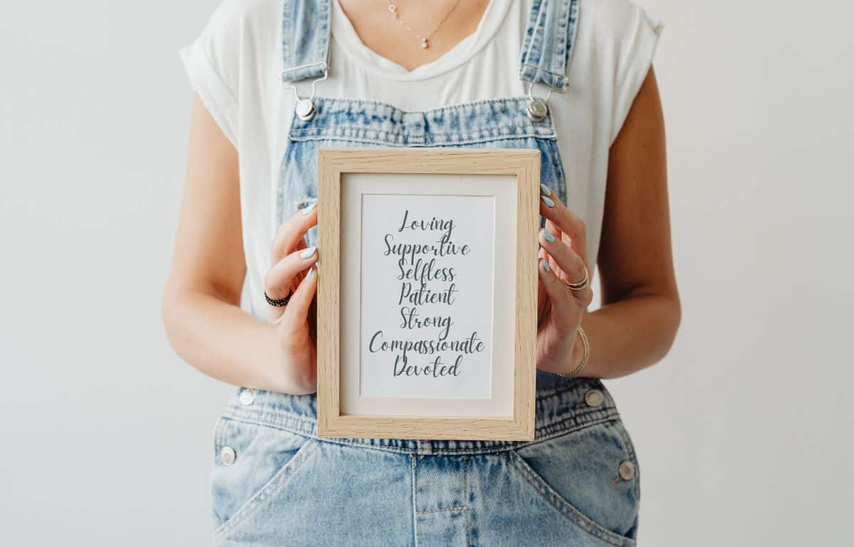 Young woman holding a frame with calligraphy words of affirmation for her mom. Affordable Mother’s Day gift 