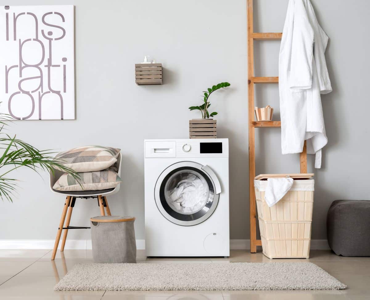 Wooden ladder leaning against wall beside washing machine. The ladder is used for hanging clothes and placing small items.