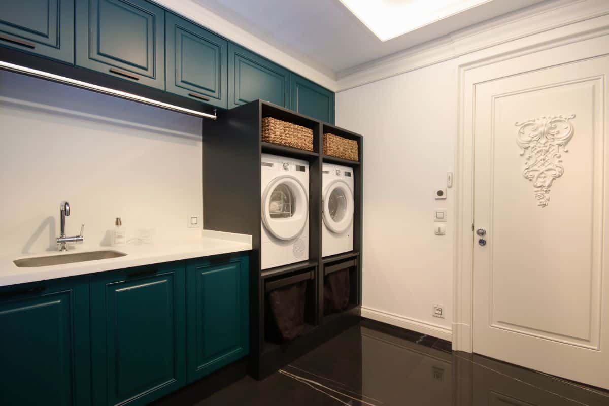 Various cabinets in laundry room. Built-in washing machine and dryer, with wicker baskets in a compartment 