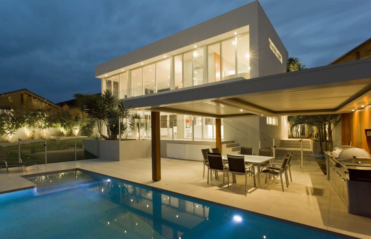 Modern house at dusk with swimming pool and barbecue in backyard