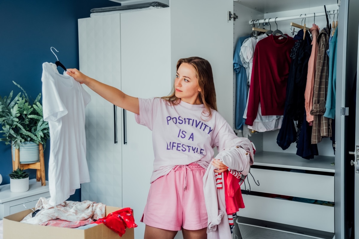 Woman selecting clothes to donate from her wardrobe.