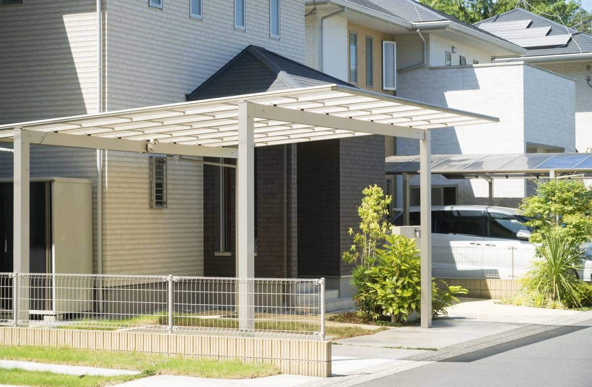 white standalone carport made of wood beside a house entrance 
