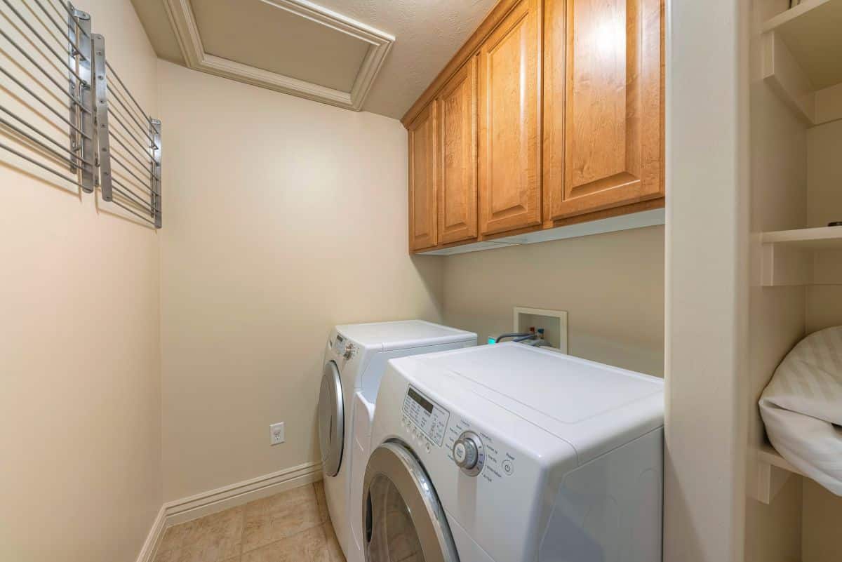 Wooden wall-mounted cabinets above washer and dryer in small laundry room