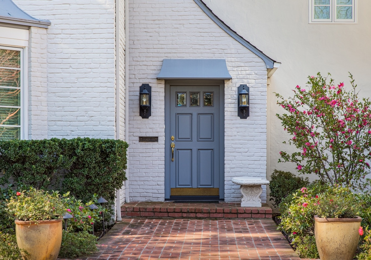 Blue front door of traditional style home surrounded by plants