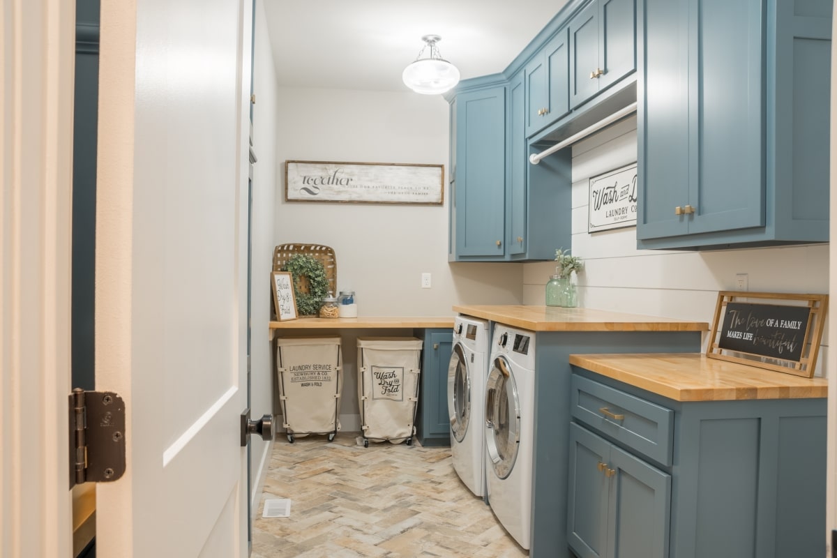 farmhouse style laundry room, rolling carts, signs, duck egg blue cabinets.