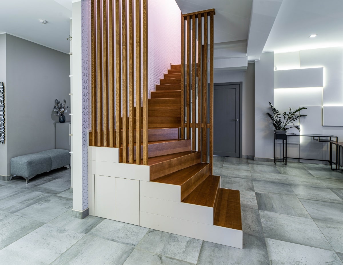 Wooden staircase to second floor with a small cabinet underneath
