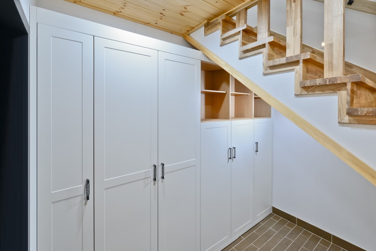 Space under stairs leading to a basement made into a storage cabinet