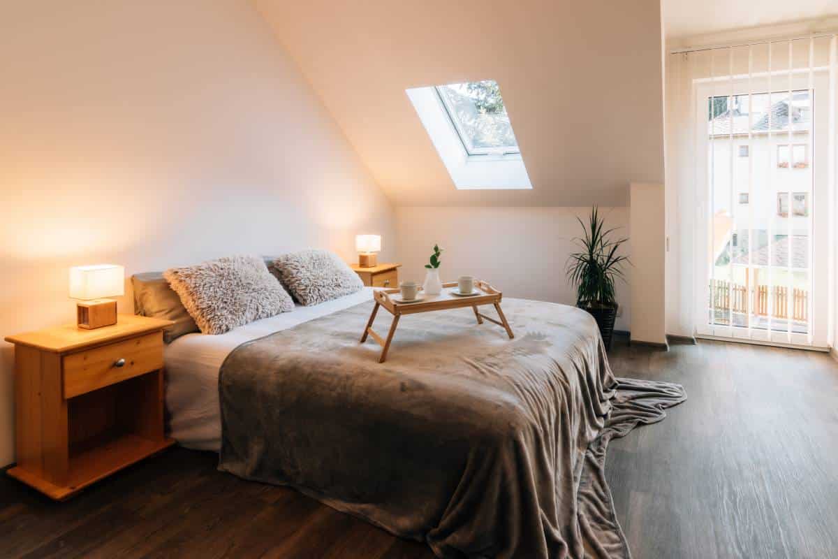 Small attic bedroom in a family house with morning breakfast service on the bed
