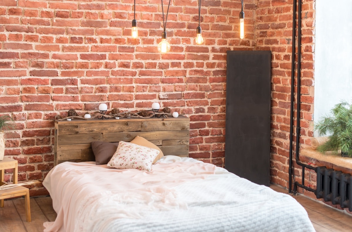 Bedroom with wooden bed, brick wall, and filament bulb as lighting