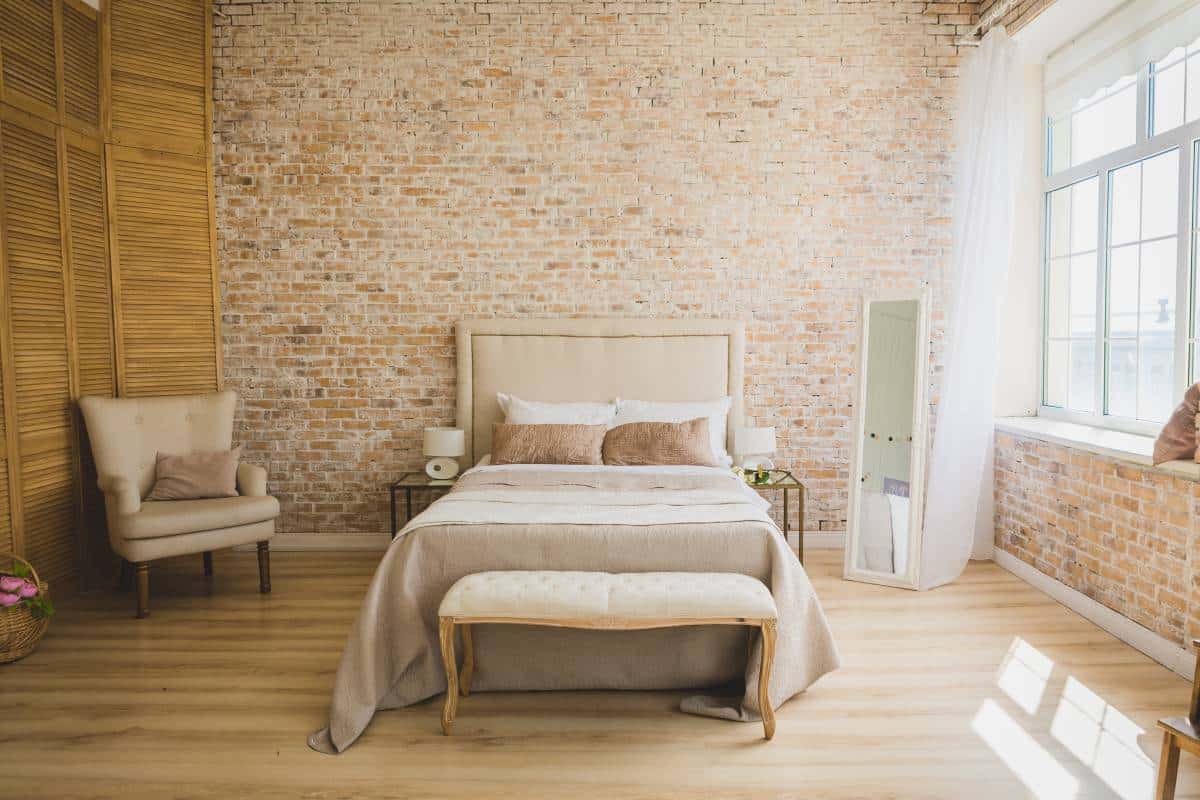 Bedroom with wooden floor and bed next to a brick wall