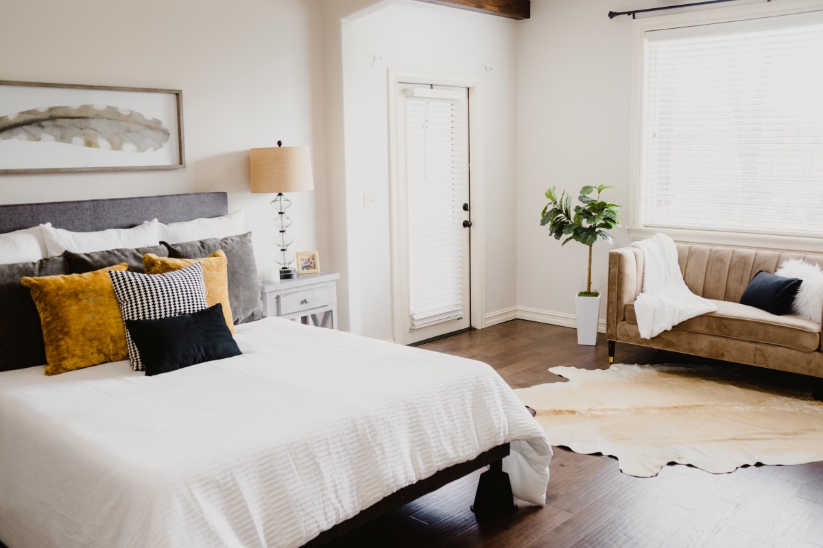 Neat bedroom with irregular-shaped rug, wide, window, and sofa