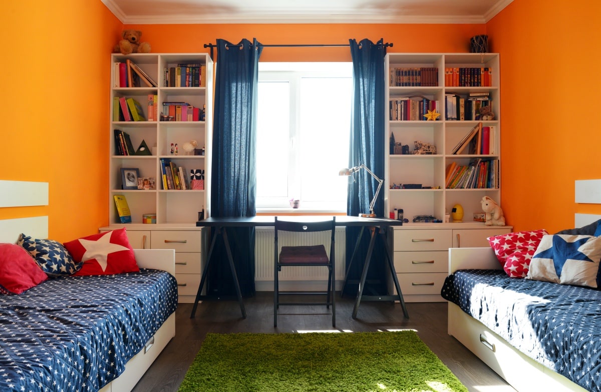 bedroom in orange and blue colors with two beds and bookcases