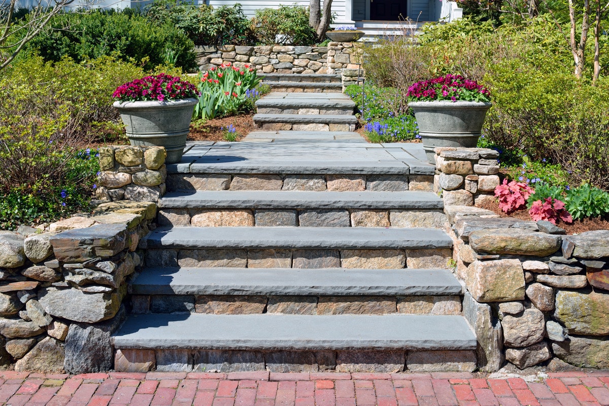 Home entrance walkway, stone wall, bluestone steps, and big planters