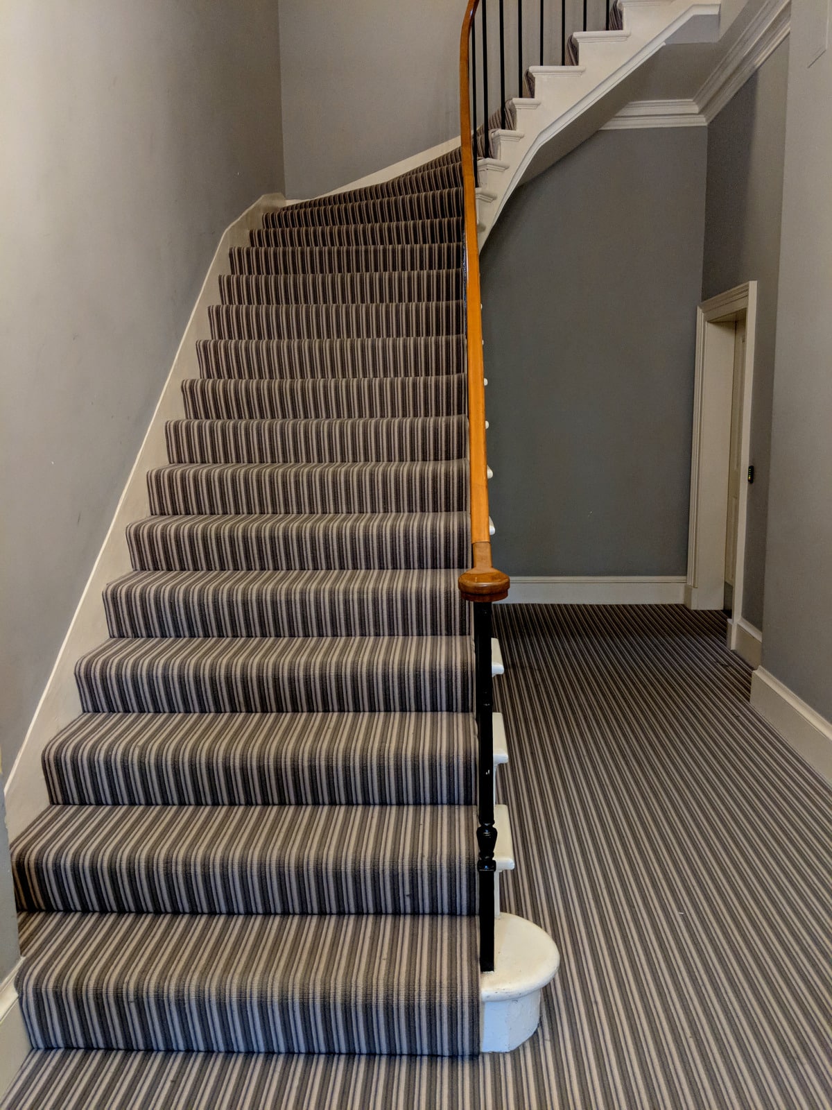 Carpeted staircase with muted neutral striped pattern