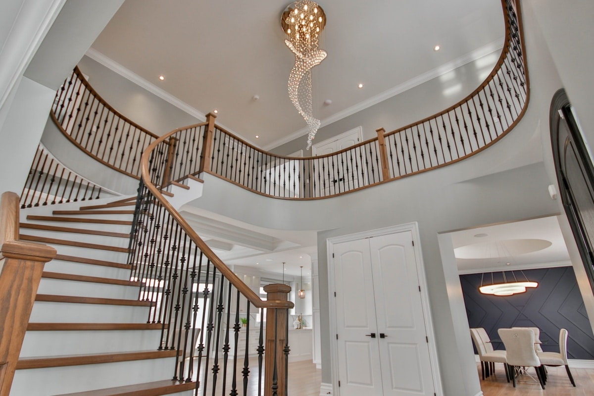 A curved staircase with a grand chandelier overhead