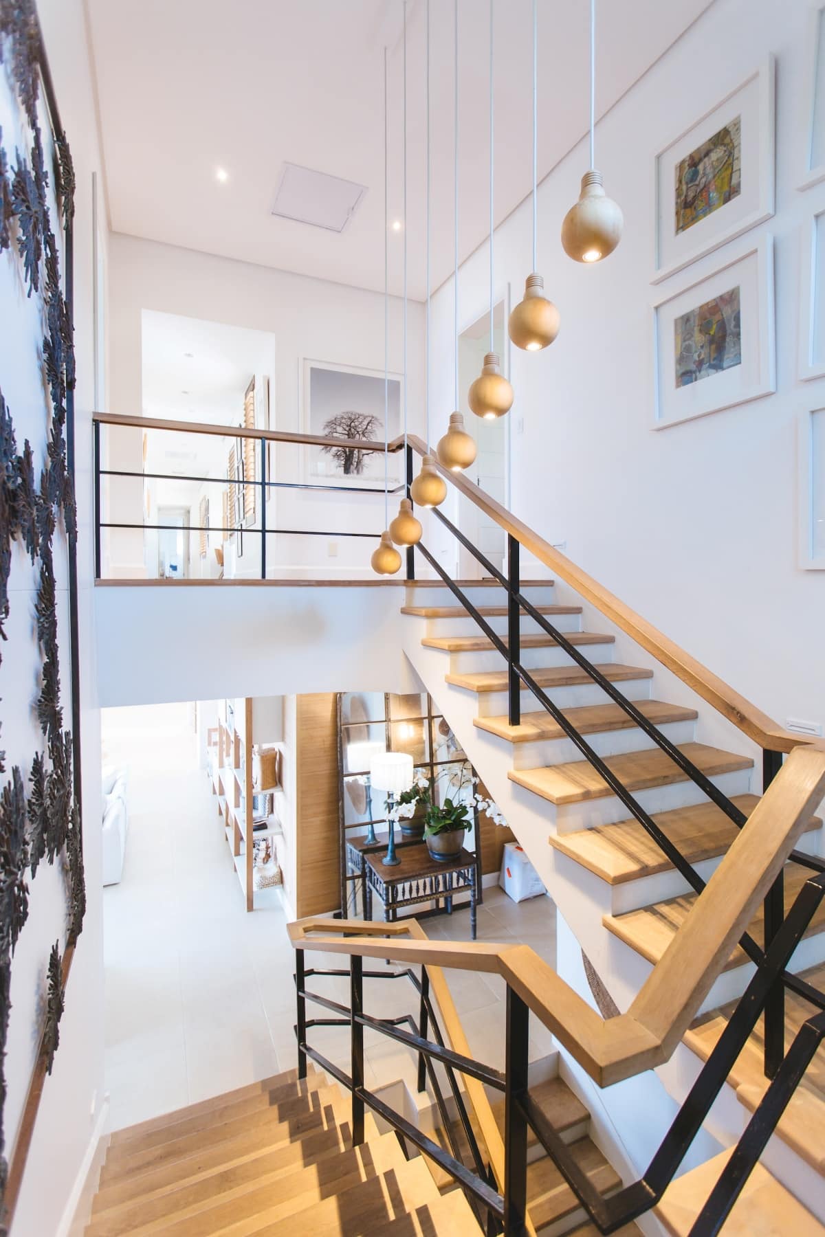 white and wood staircase with pendant lights above it