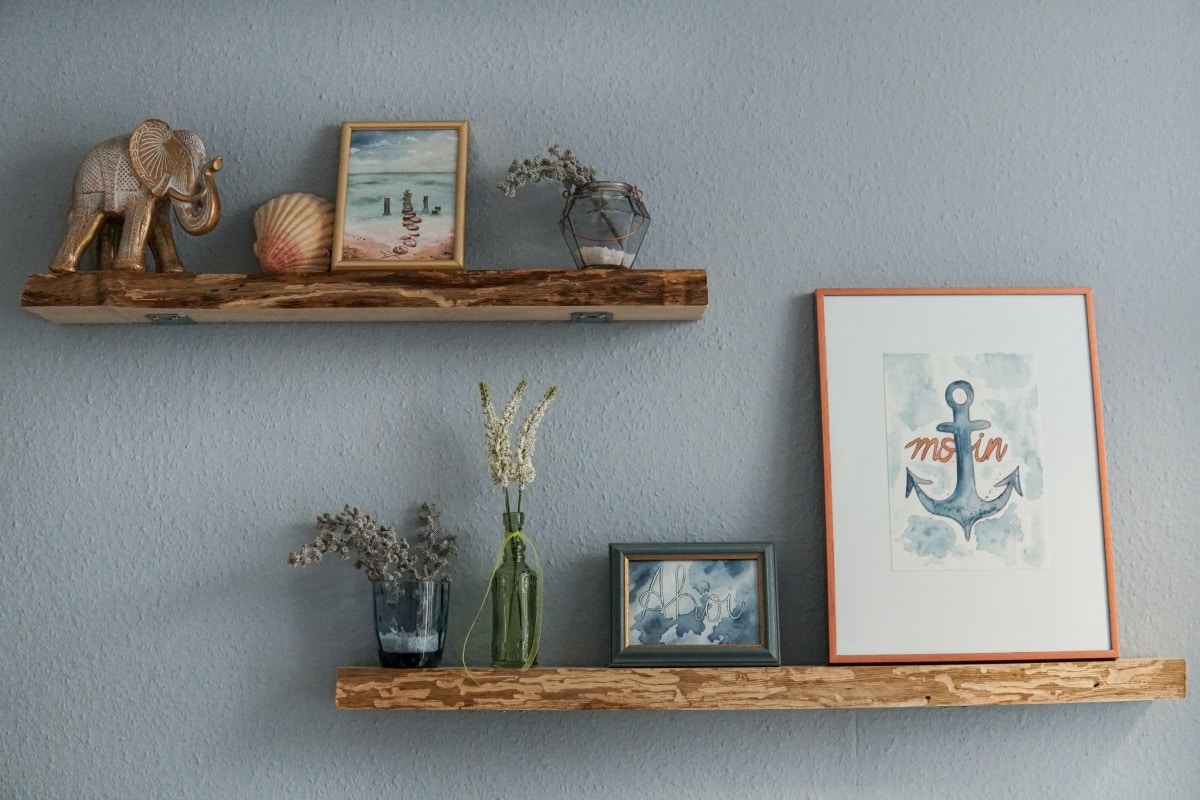 floating shelves with white flowers in clear glass vase and framed photos