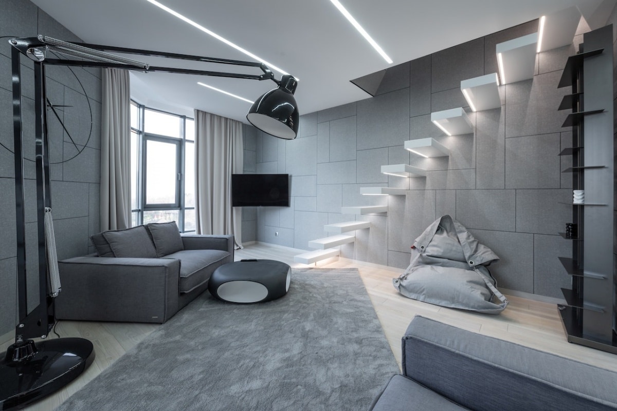 Studio with sofa on carpet, lamp, and stairs with LED lighting