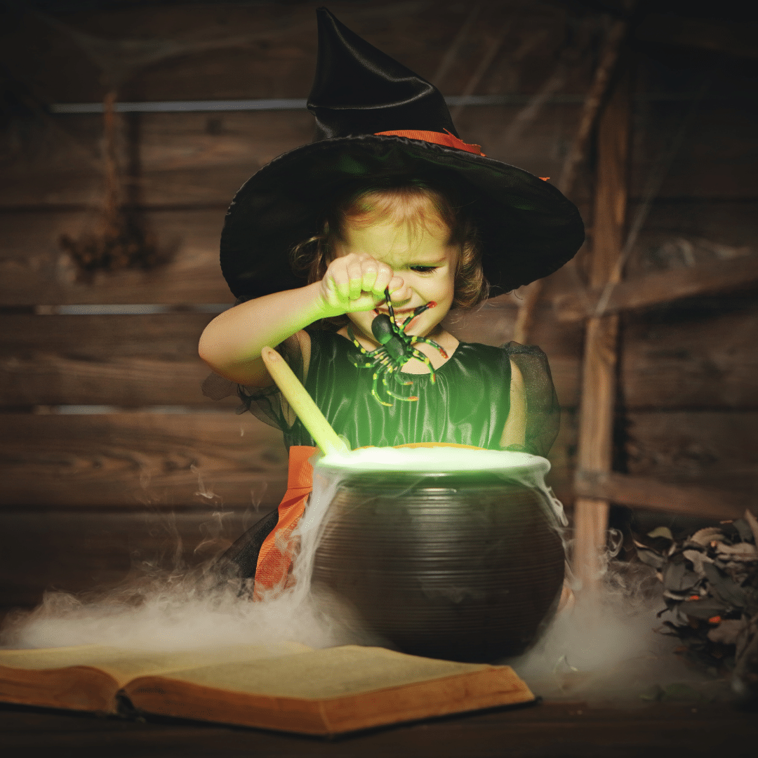 A little girl playing with a DIY witch's cauldron for Halloween.