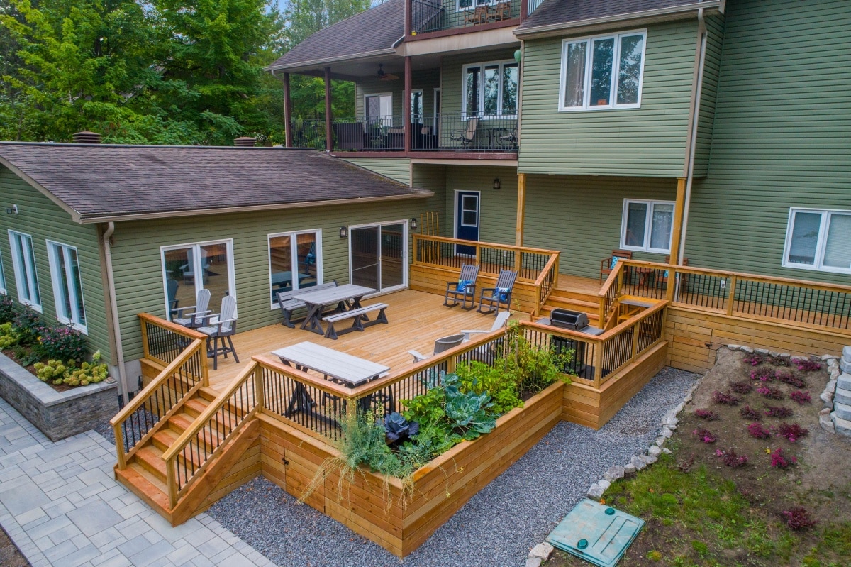 a deck with chairs and tables on it near a home