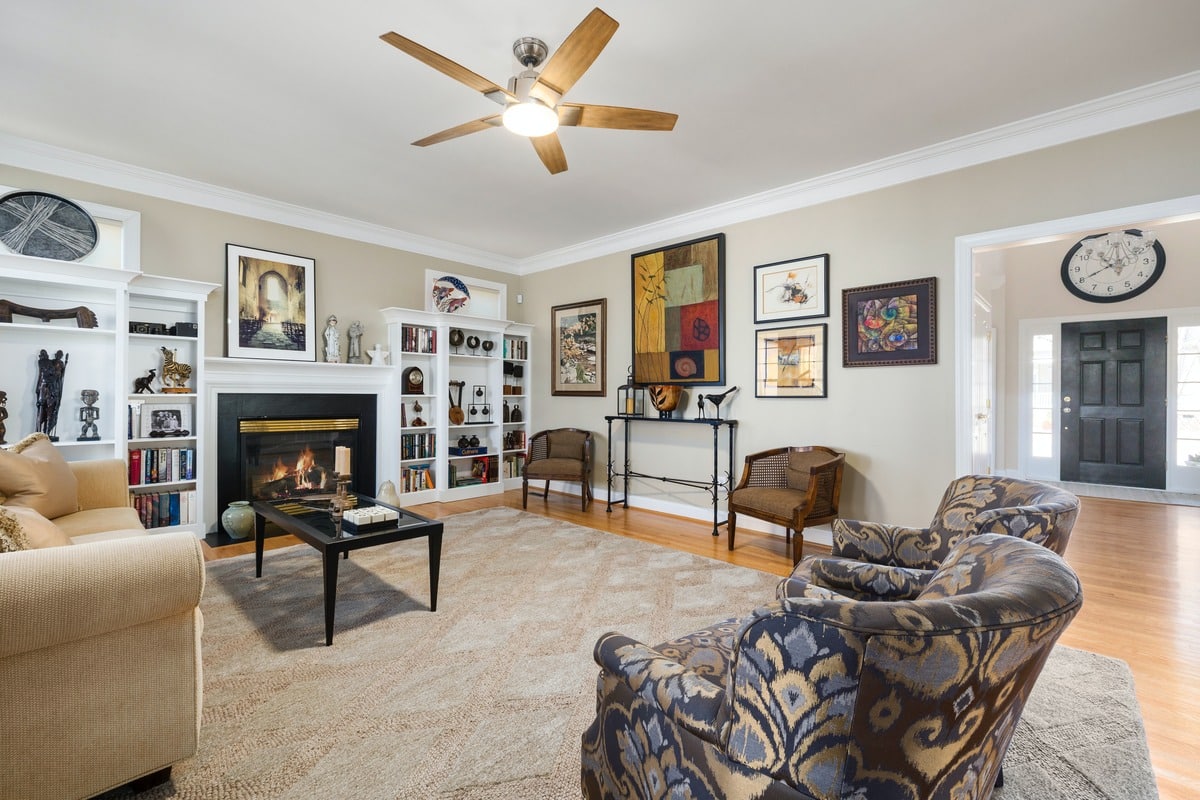 A living room with a brown ceiling fan and paintings on the wall