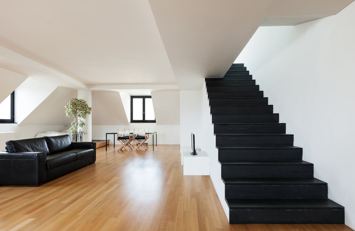 interior of a modern loft with hardwood floors and black stairs