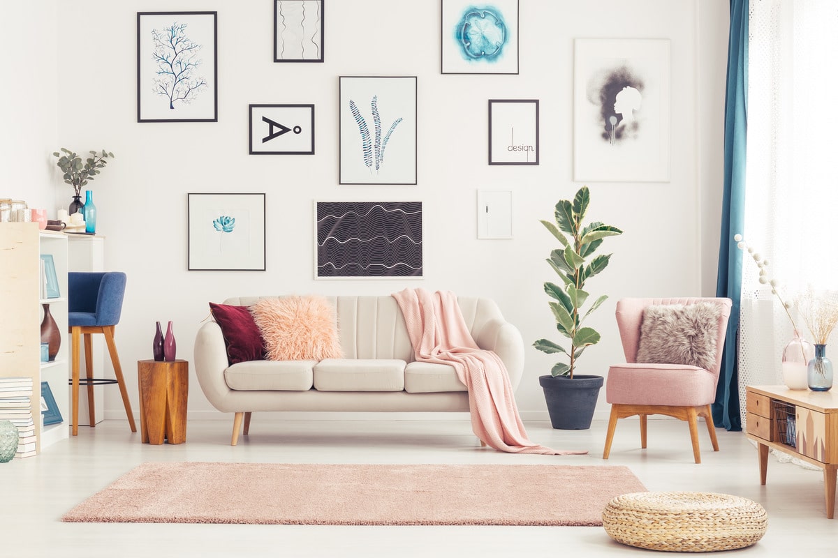 Interior of a pink living room with white couch, pink armchair and posters spread out on the wall