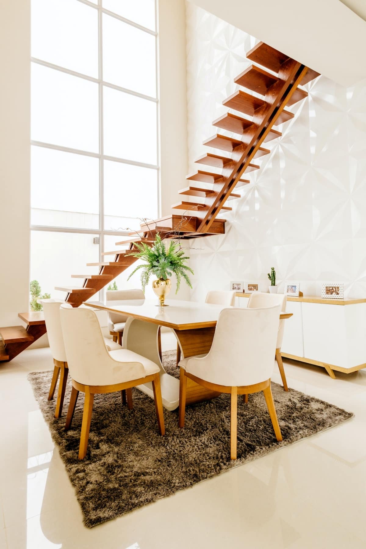 dining table with a rail-free wooden staircase next to it