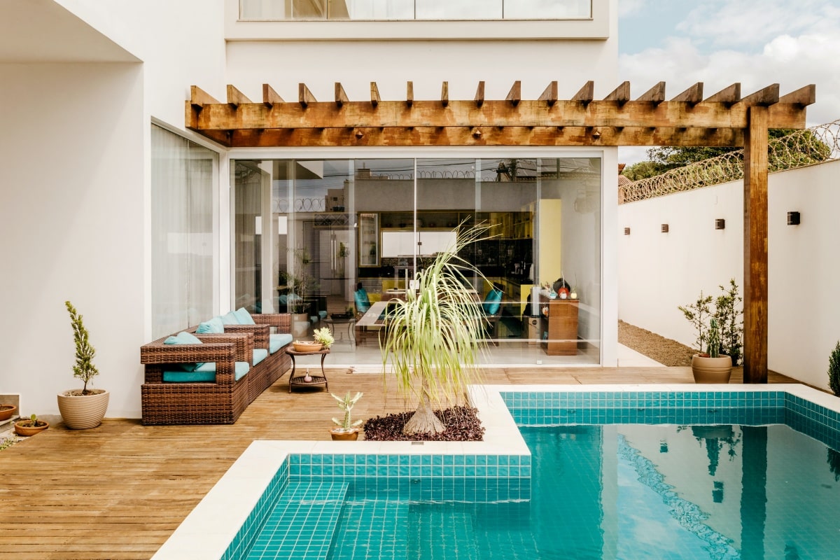 wooden decking with woven seating under pergola and near swimming pool