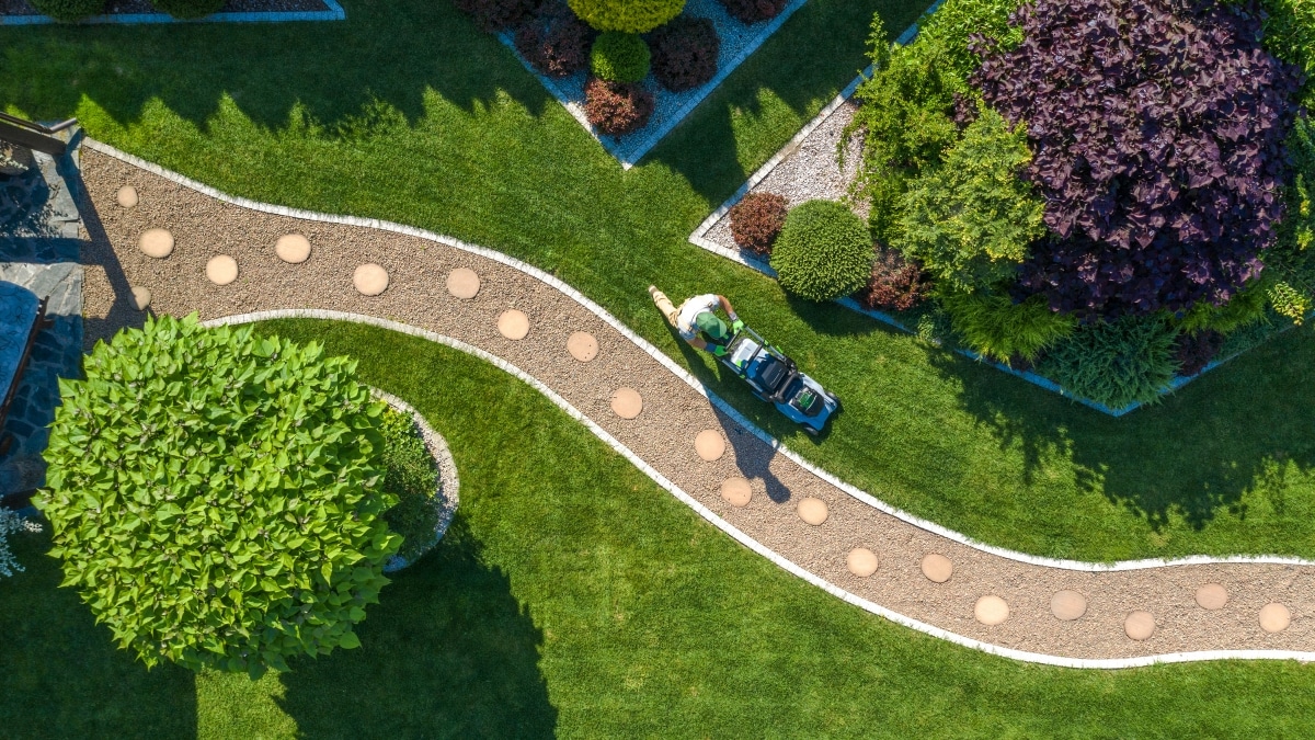 A professional landscaper mowing a beautiful backyard.