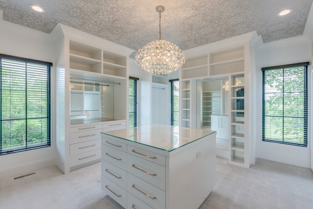 Luxurious closet with ample space, empty shelves, and chandelier