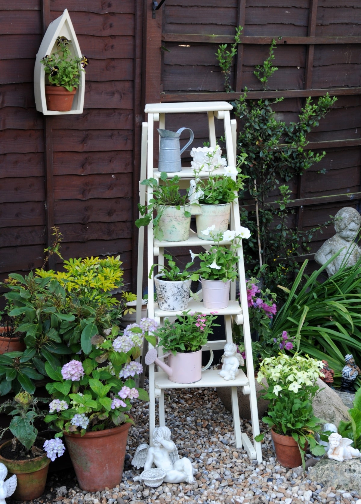 Plants in varying pots placed on each step of a stepladder