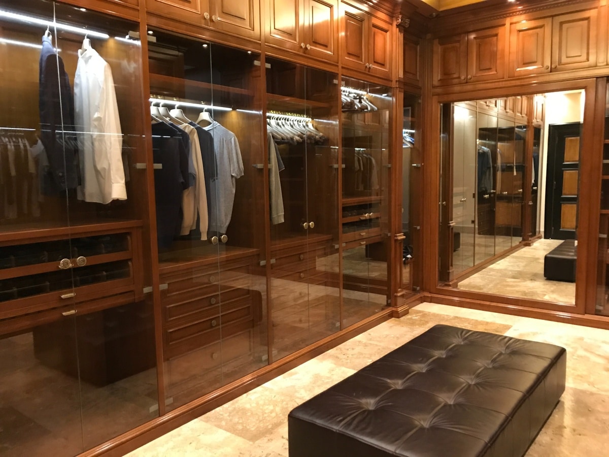 Walk-in dressing room with wood cabinets and leather seat