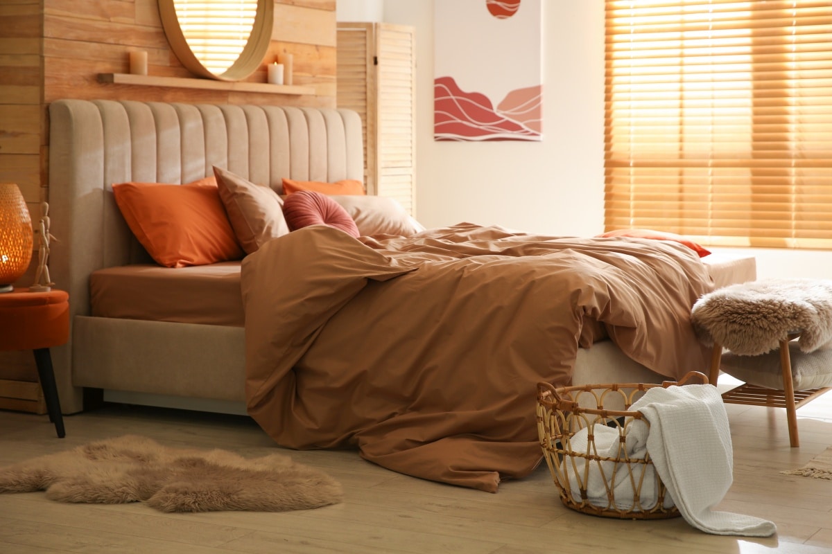 Bed with brown and orange linens in cozy bedroom