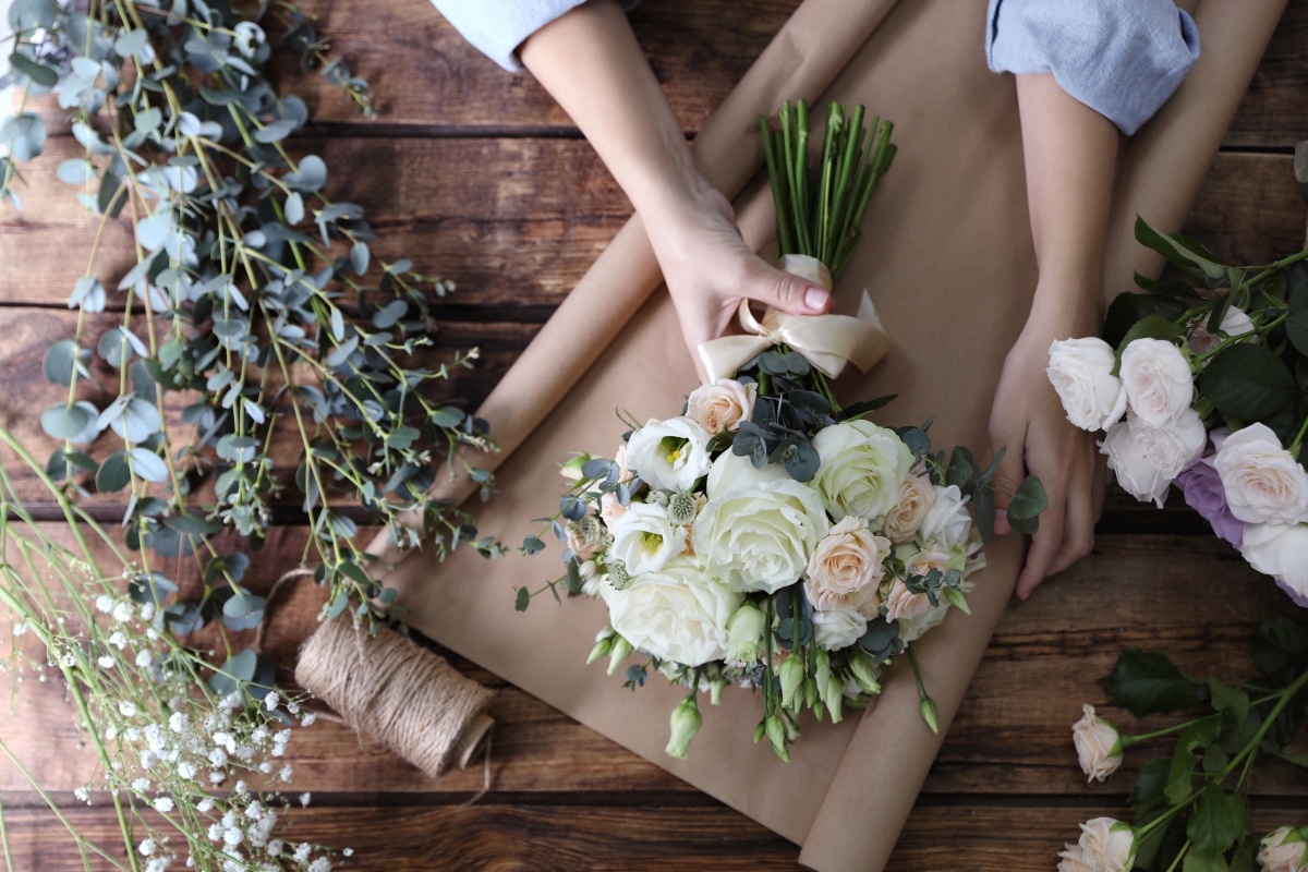 A professional florist arranging a beautiful bridal bouquet for a wedding.