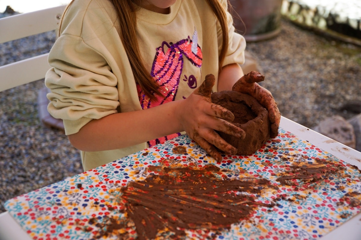A girl playing with clay in an outdoor mud kitchen