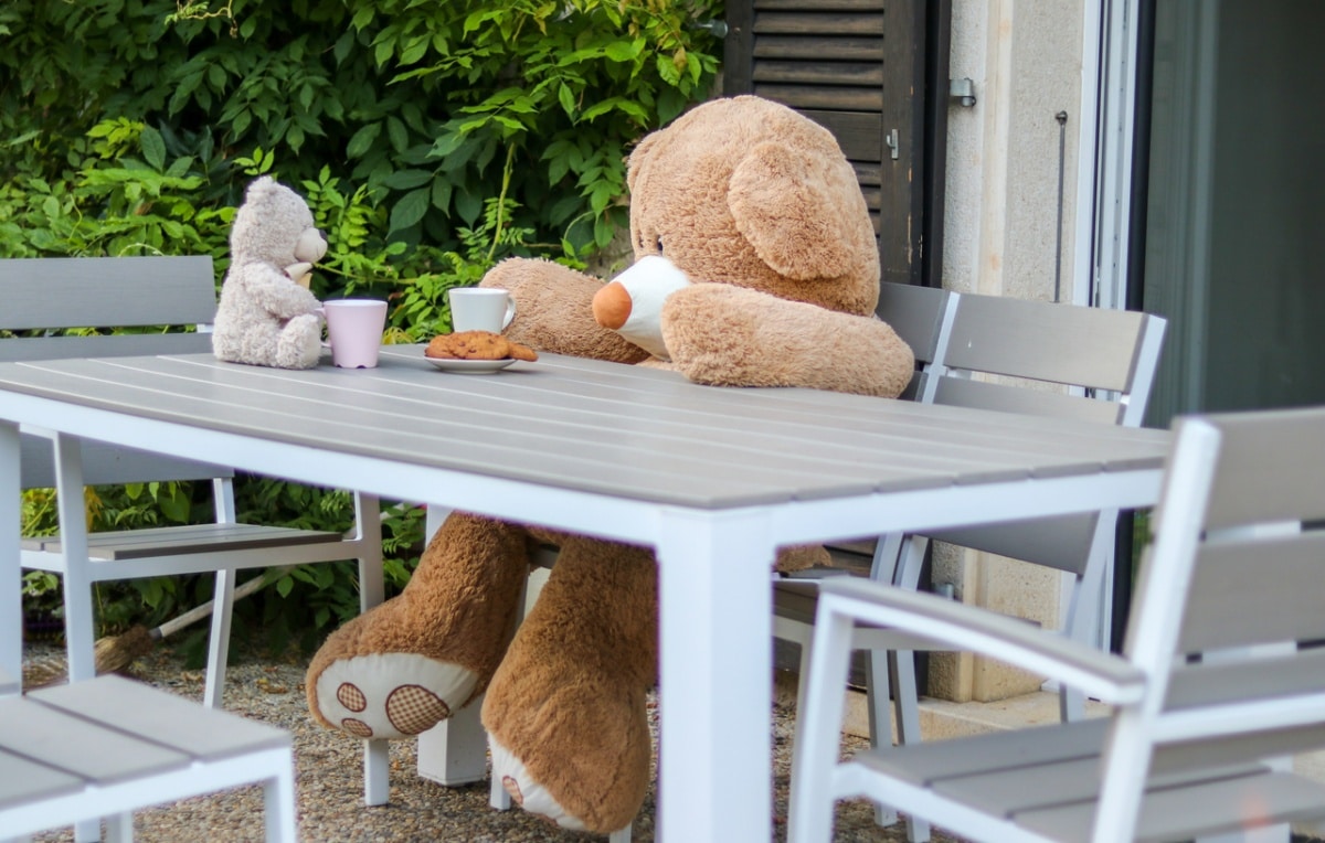 Outdoor dining area with two teddy bears having a sit