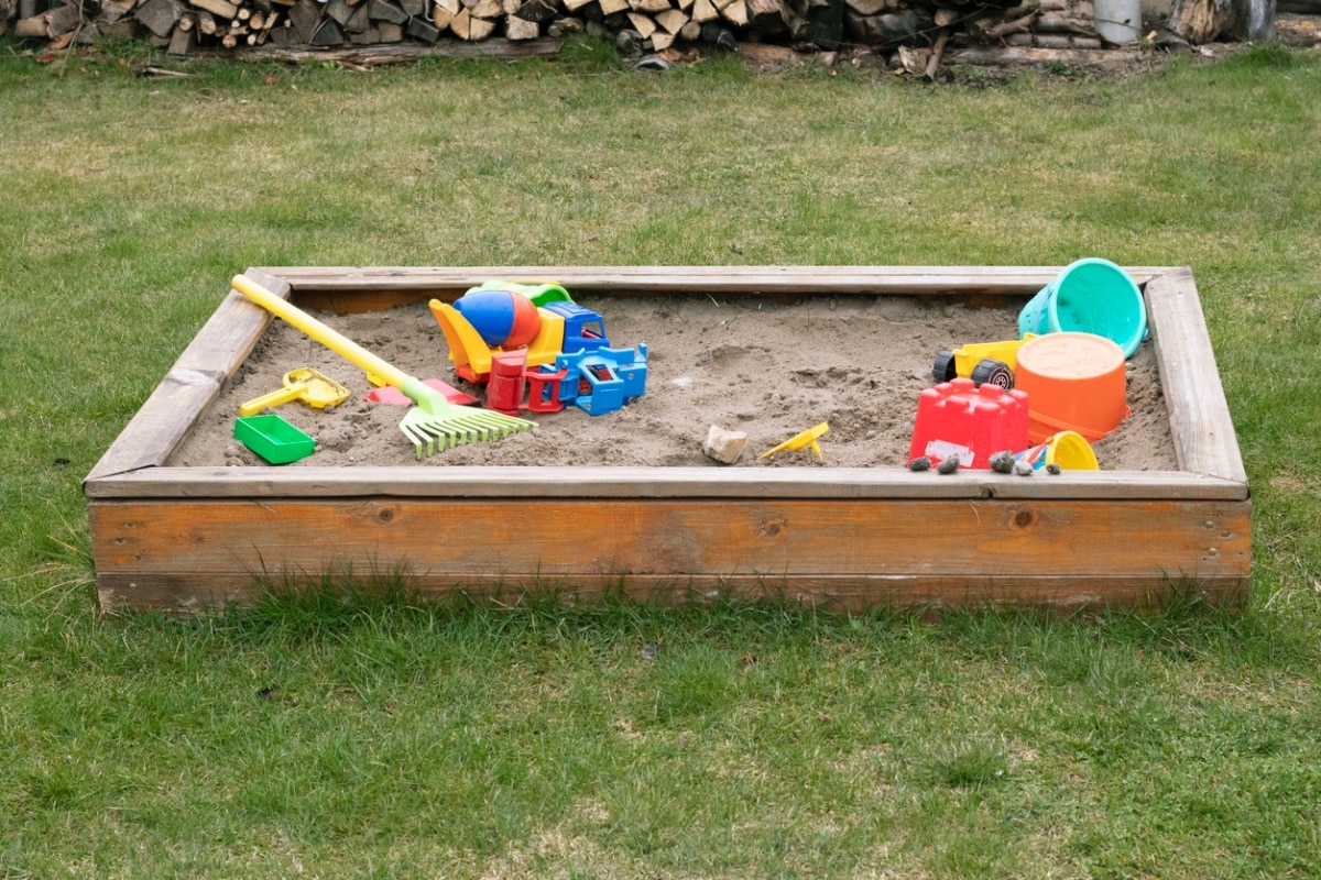 Children's sandpit with toys on green grass