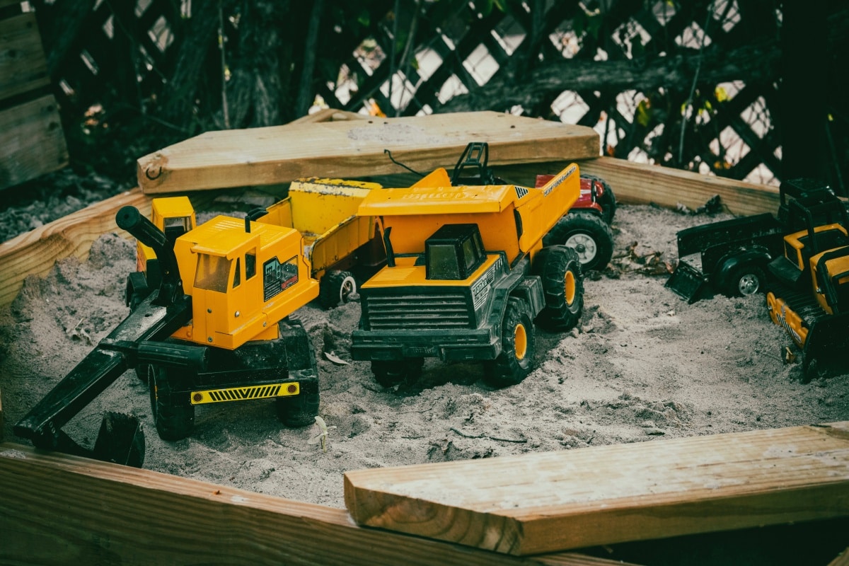 Sandpit with yellow toy trucks