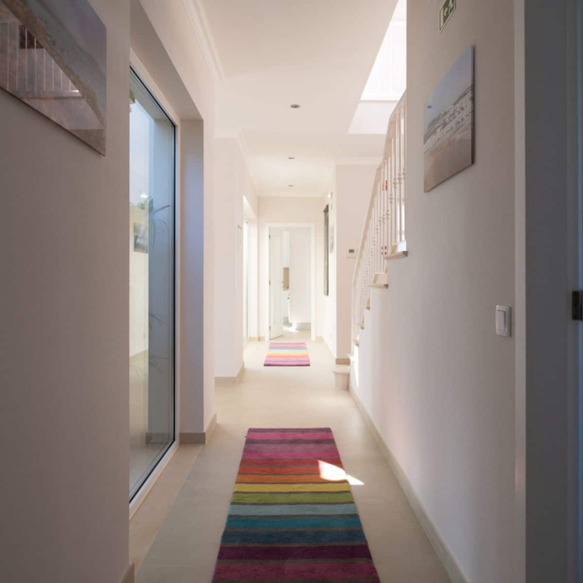 a long hallway with two rainbow-colored rugs