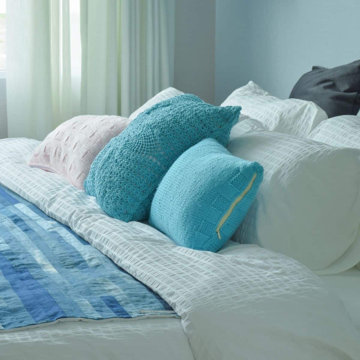 a bed with a blue duvet and teal and white pillows