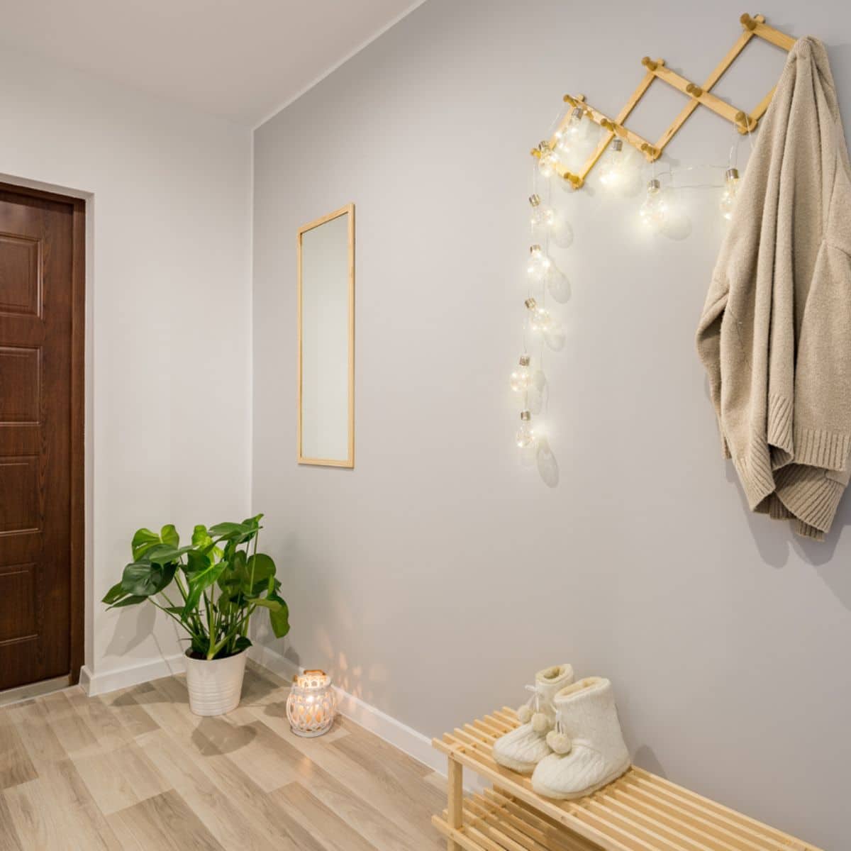 a hallway with a light grey wall, a coat hook, and fairy lights