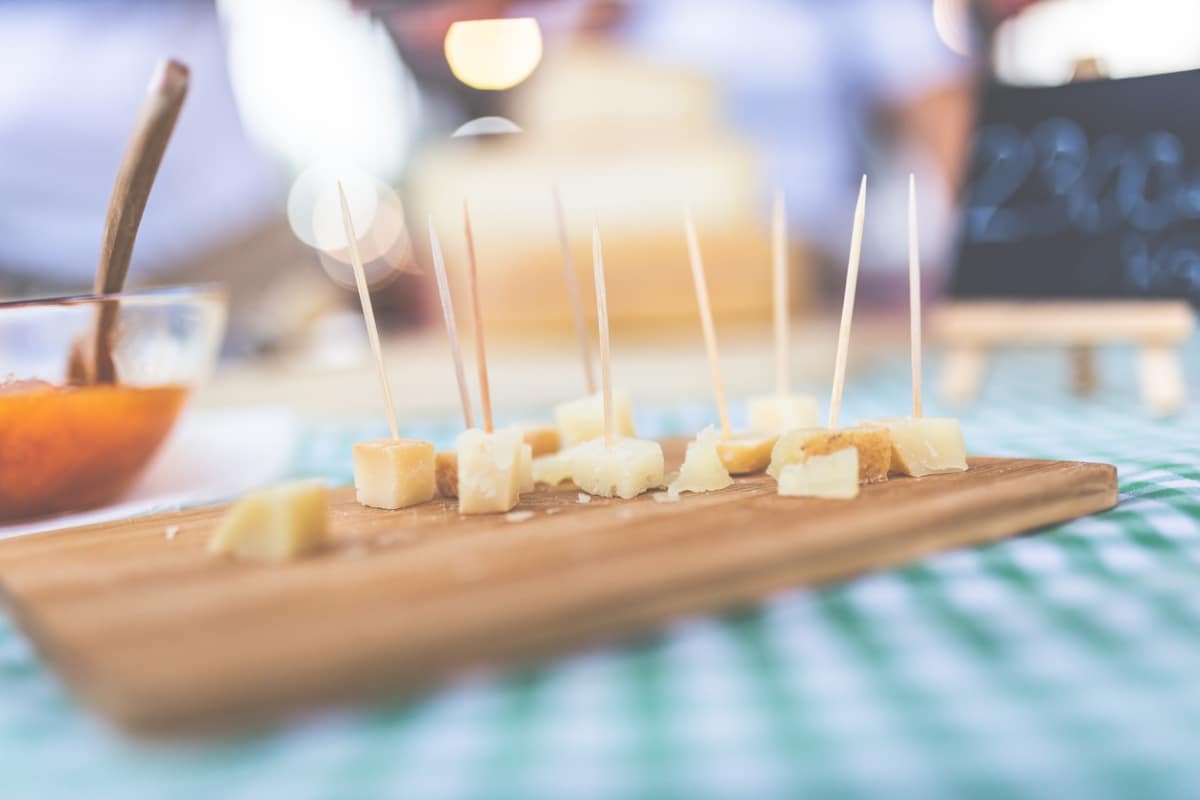Cubes of traditional handmade cheese with toothpicks on street food market stand