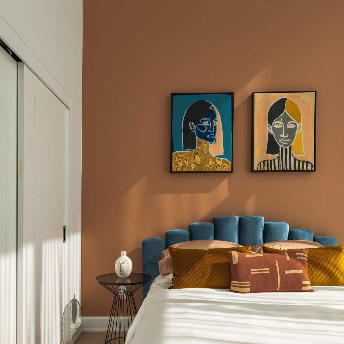 A teal and orange bedroom with paintings on the wall
