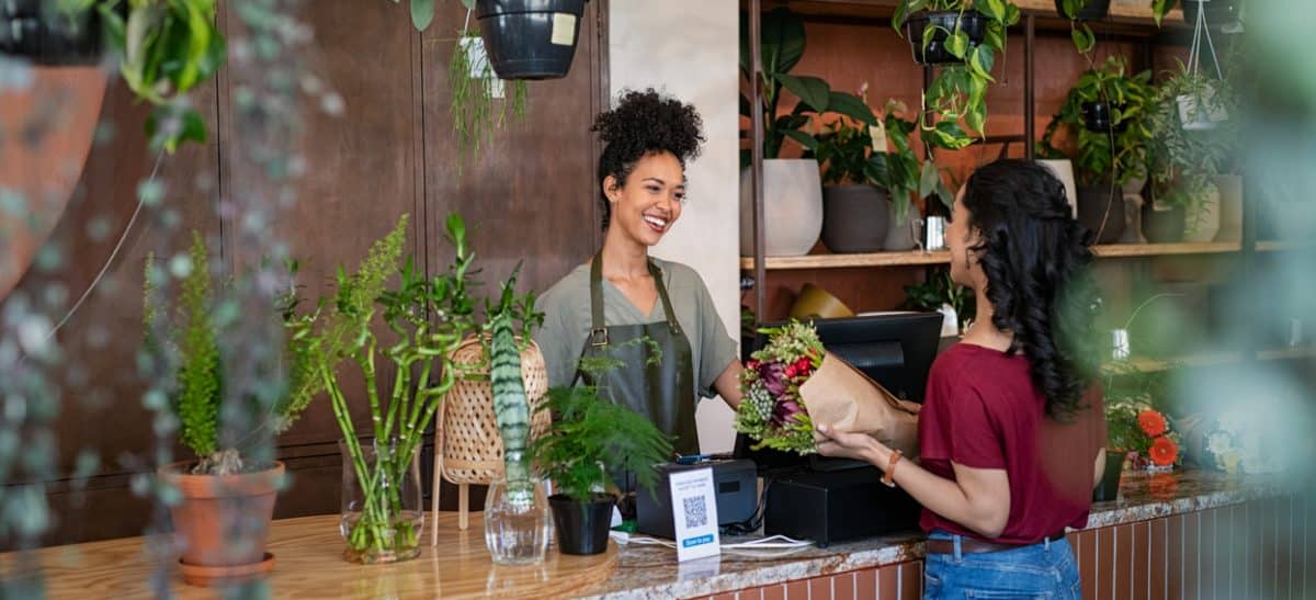 Happy florist selling plants and flower to client