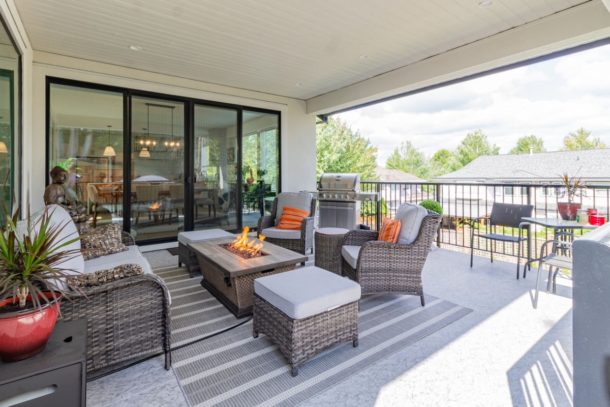 A spacious deck with a fire pit table heater and a BBQ grill.