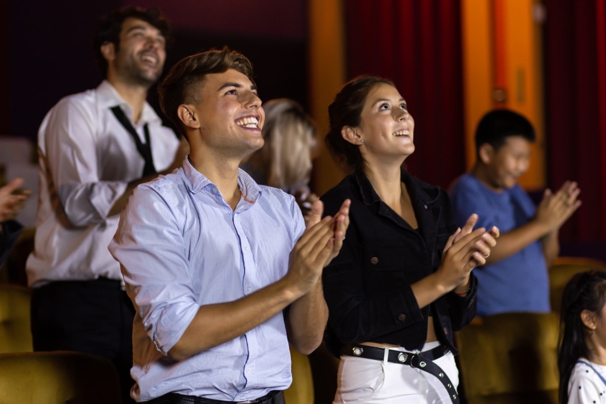 An audience standing and applauding after watching a live musical.